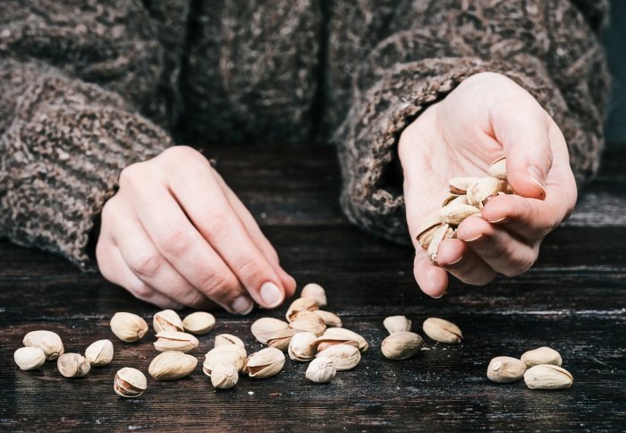 Hand scattering pistachios on a table