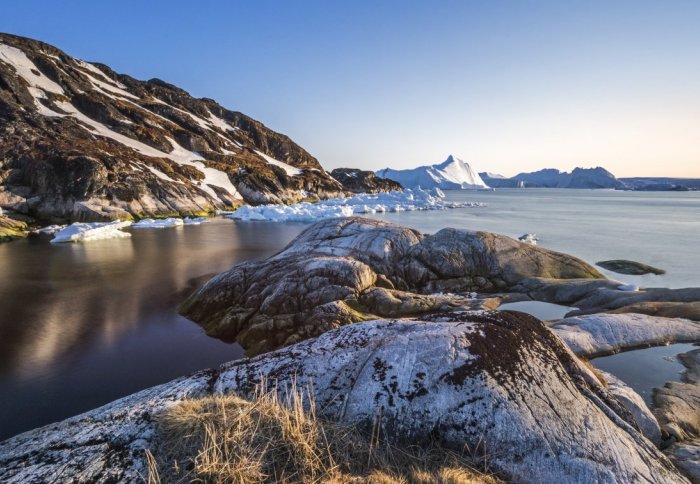 An iceberg seen form a rocky outcrop at sunset