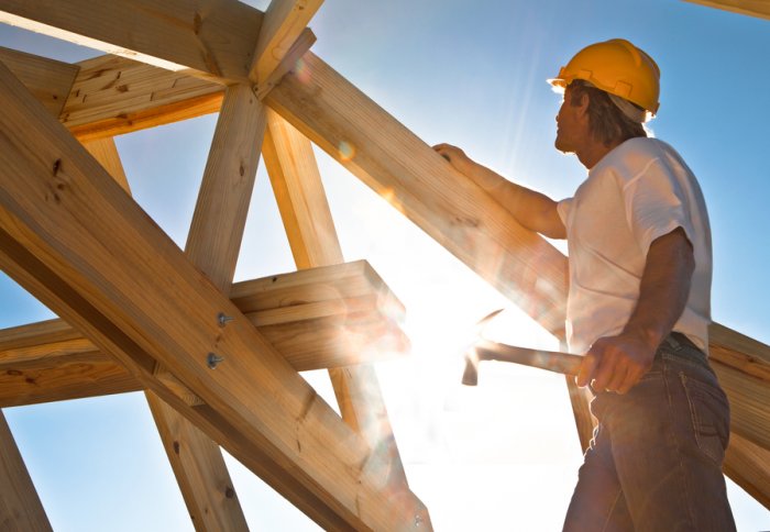 A construction worker builds a wooden frame in the sun