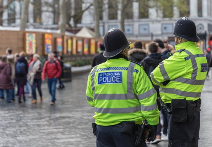 Two London policemen looking at a crowd of people