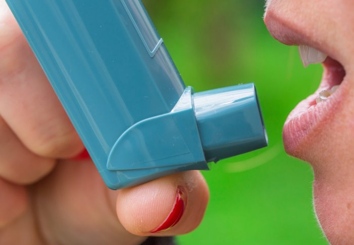A woman prepares to breathe in an asthma inhaler