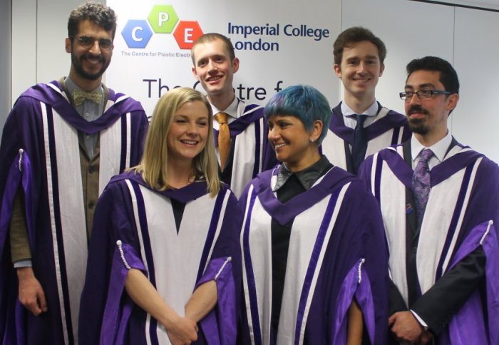 Graduating students dressed in Imperial College purple and white PhD graduation grounds, two women and four men