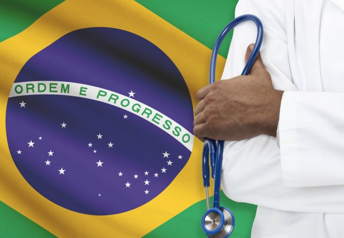 Doctor stands next to Brazilian flag