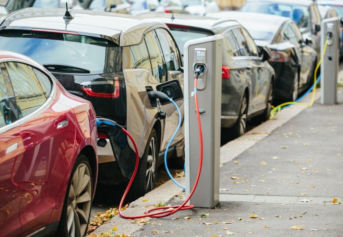 Electric cars plugged into charging stations along a street