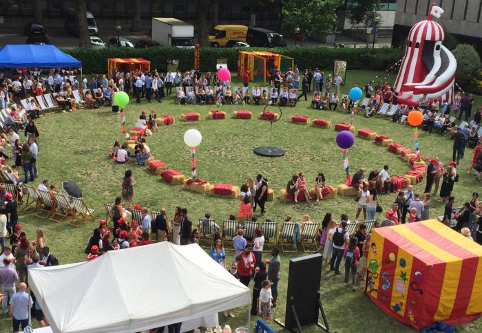 Lawn with helter skelter, coloured tents and people milling about
