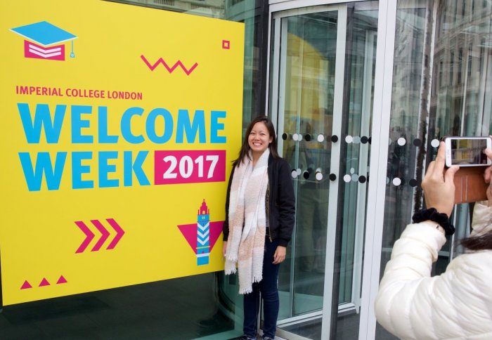 A new student poses for her mother's camera next to an Imperial Welcome Week sign