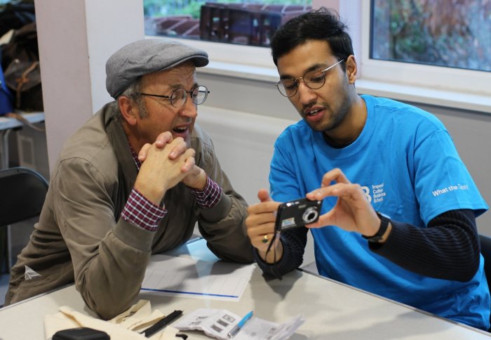 A student volunteer helps an elderly resident with a digital camera