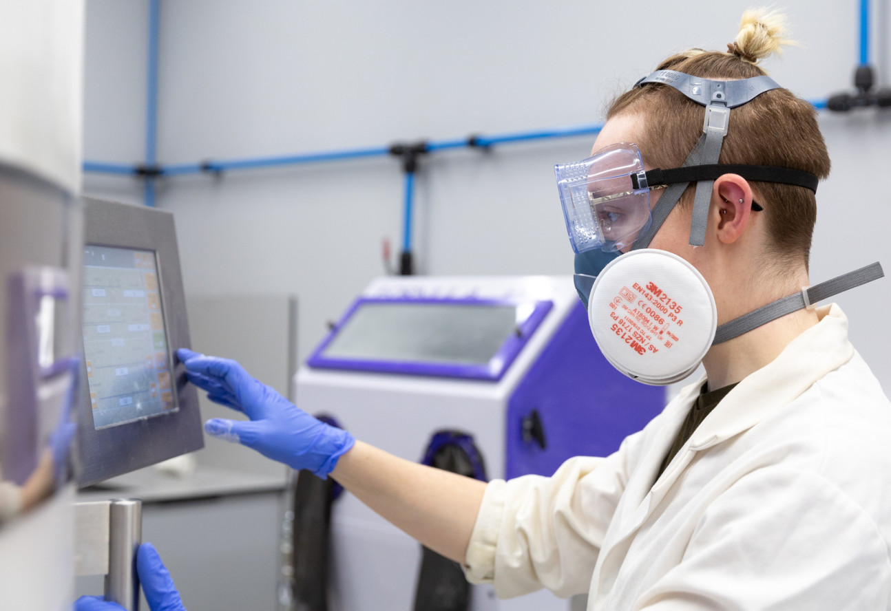 Man  in lab coat and face  mask works on laboratory computer