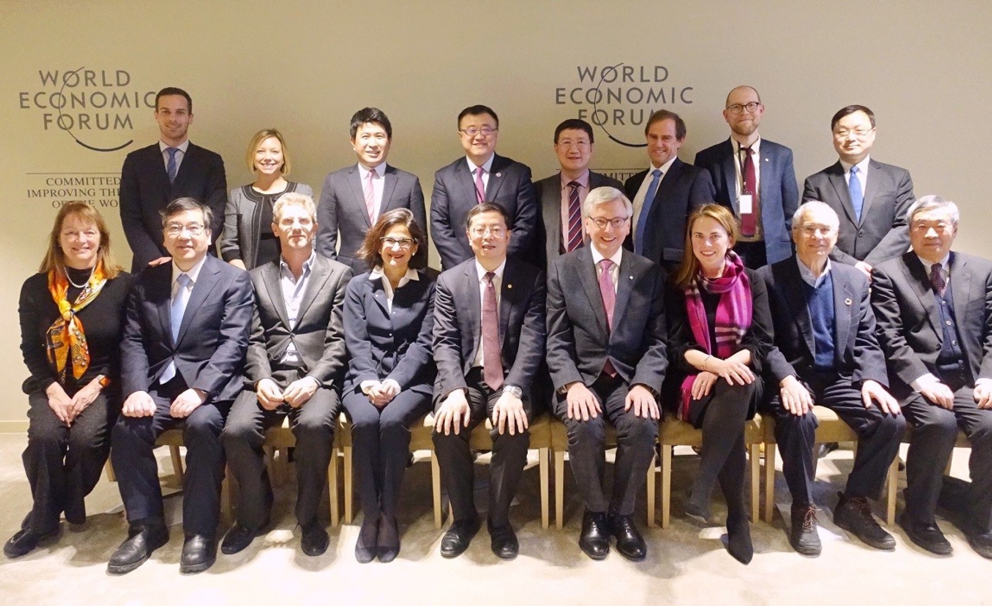 17 people pose for a photo in front of signs that read "World Economic Forum"