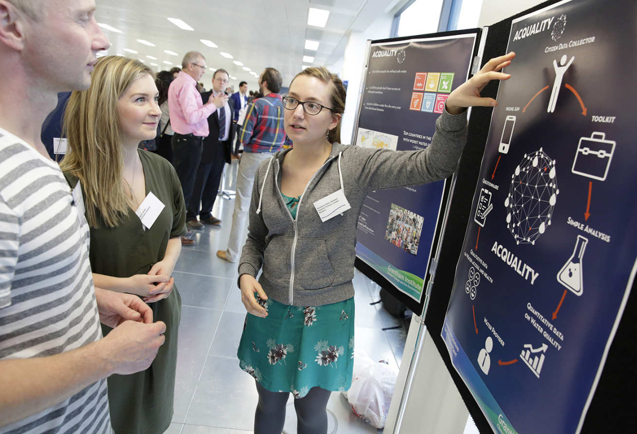 Student Geraldine gestures to a poster while two people watch