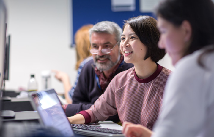 Students around computer smiling