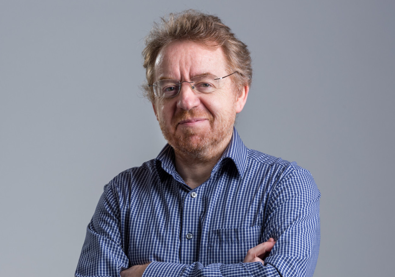 White man wearing blue shirt with arms folded