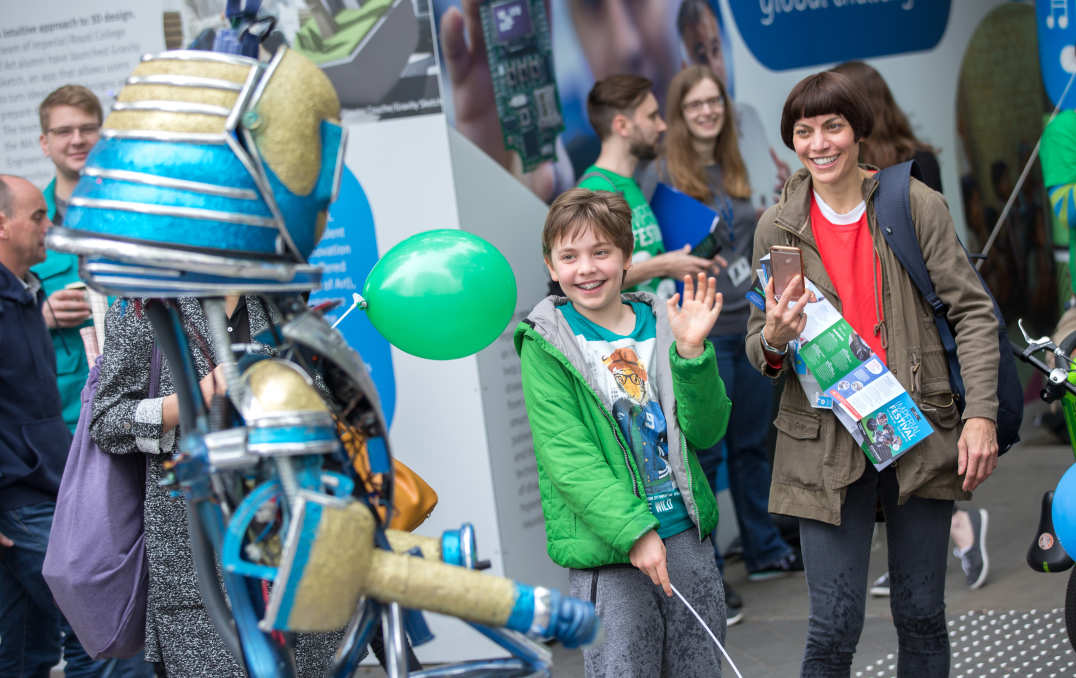 A boy waves at a robot