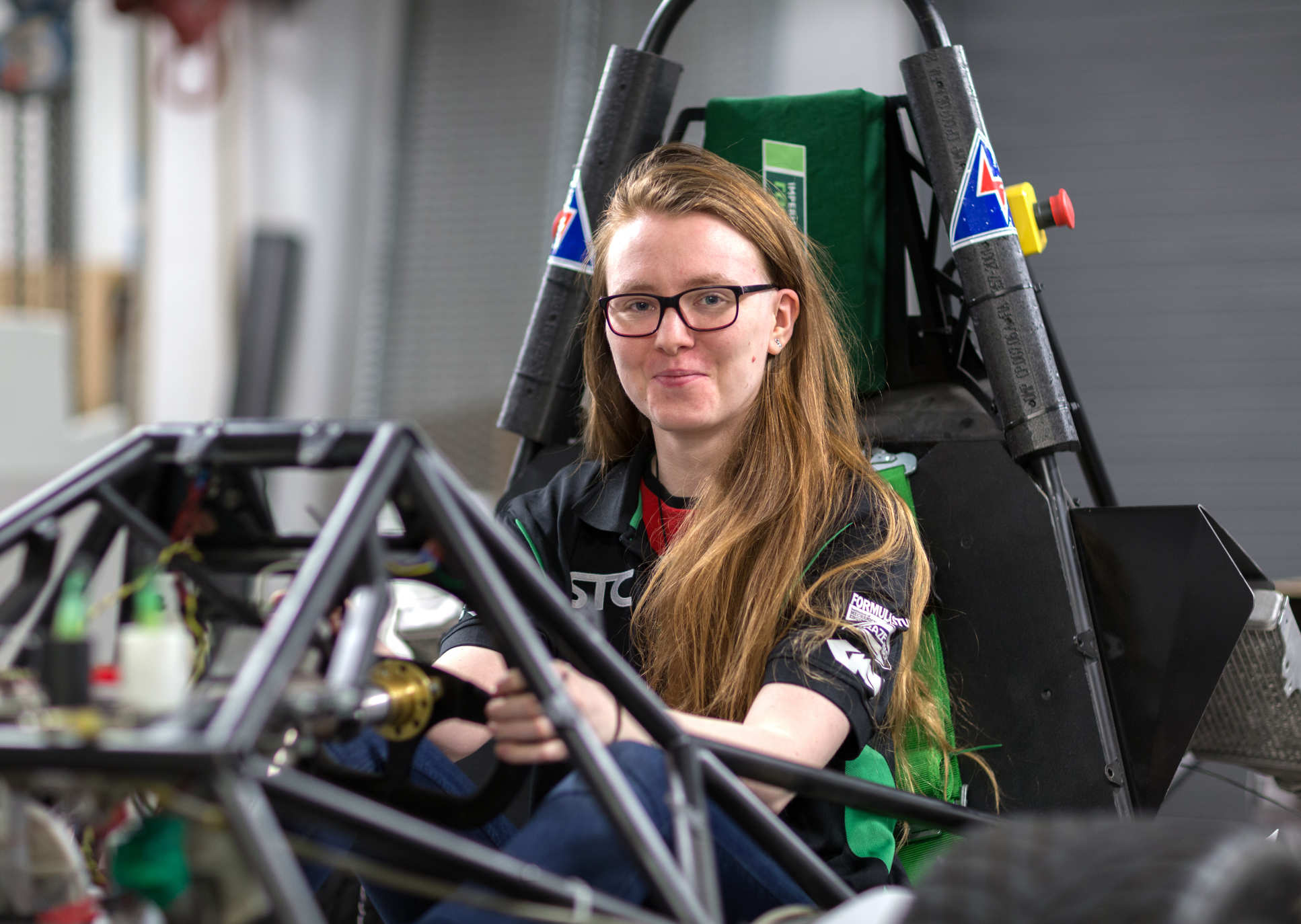 Female student sat in a formula racing car