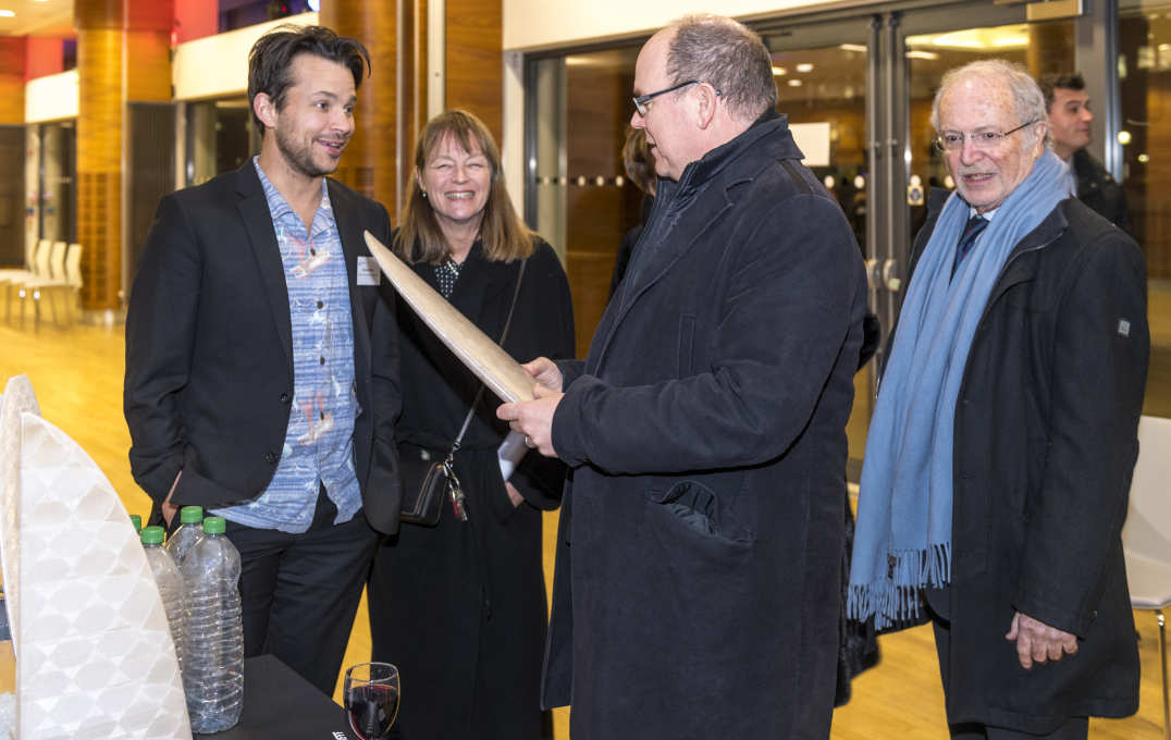 A student giving the prince a surfboard