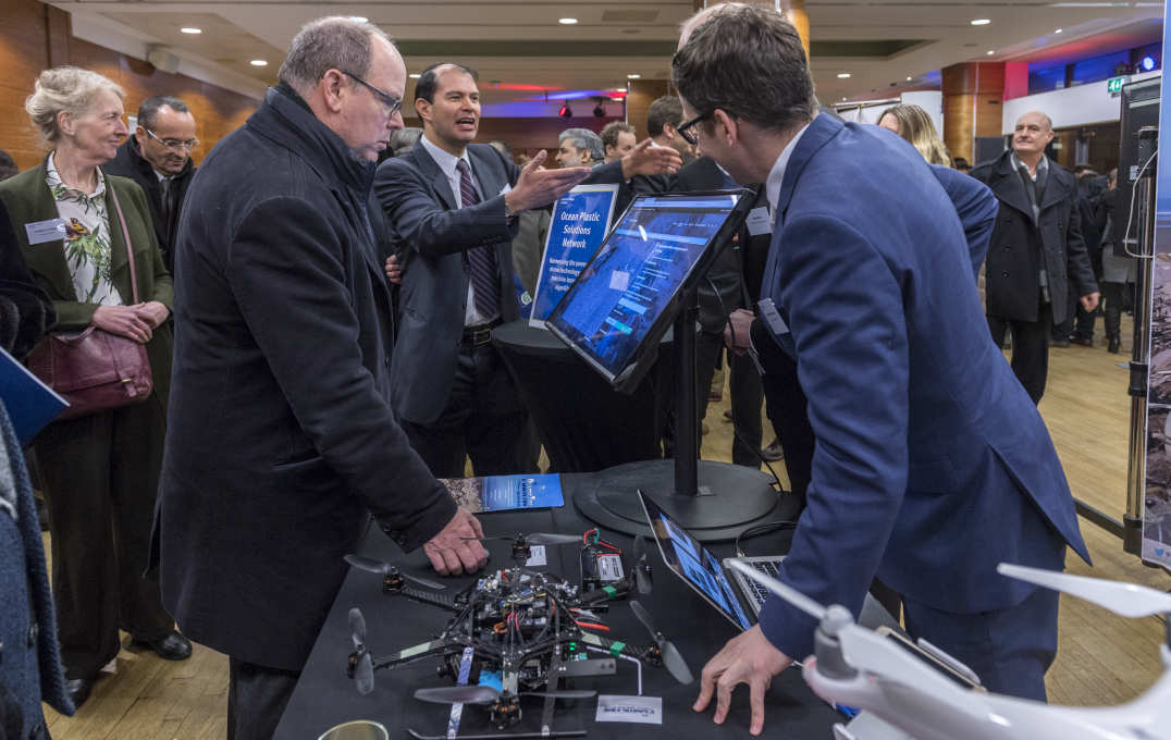 The prince talks to a student over some screens and a drone