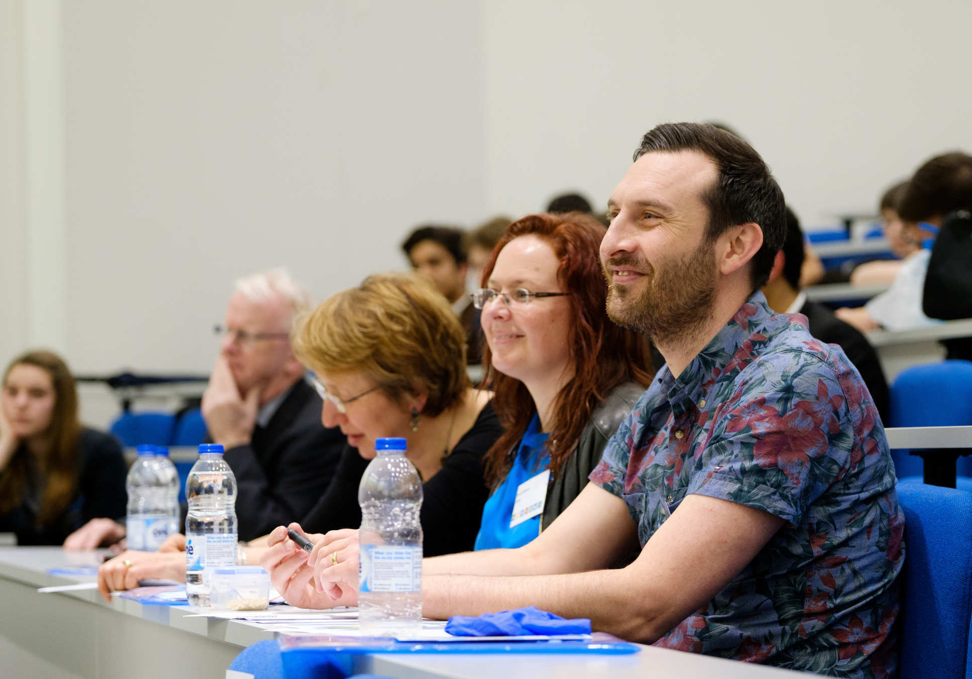 The three judges and audience watching a team presenting their ideas