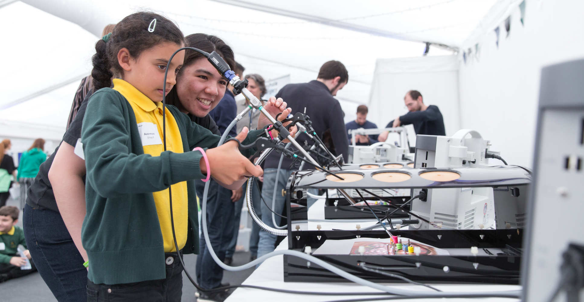 A local school pupil tries out surgical technology with a student volunteer at the Imperial Festival Schools Day in April 2018.