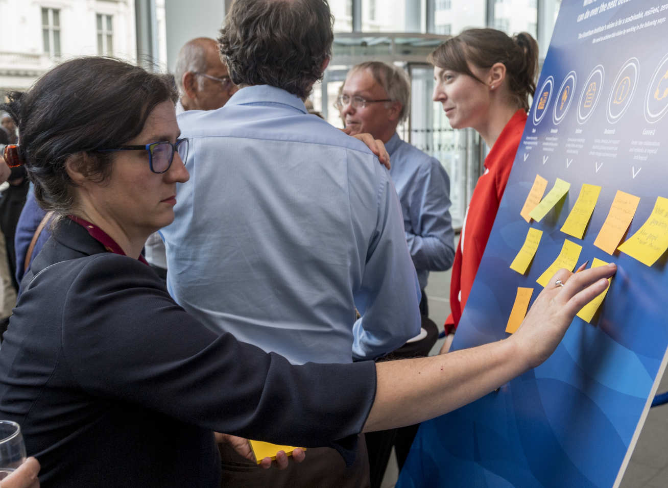 Lady writes on post-it note before sticking it to a comment-board