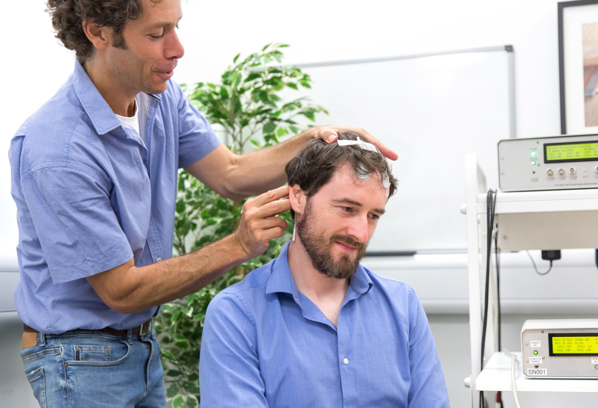 Dr Nir Grossman demonstrates his brain stimulation work on a seated man