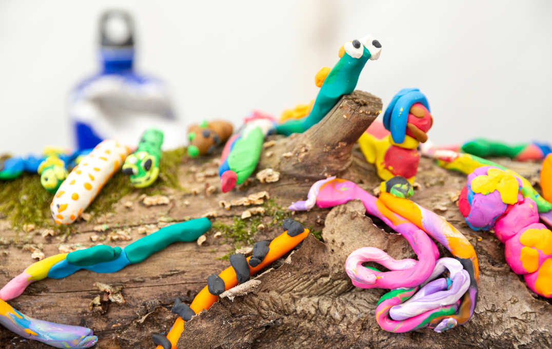 Colorful Plasticine worms on a log