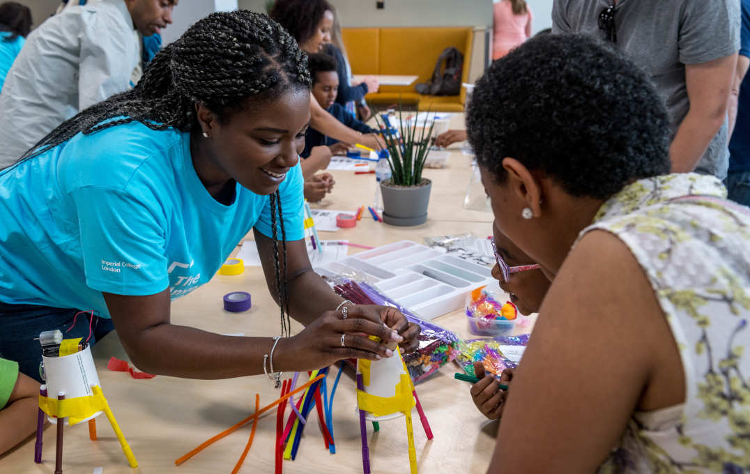 A member of the Outreach team helps a child build a robot