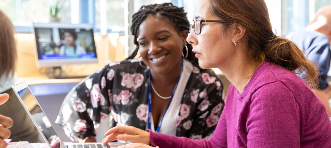 Two people using a laptop and smiling