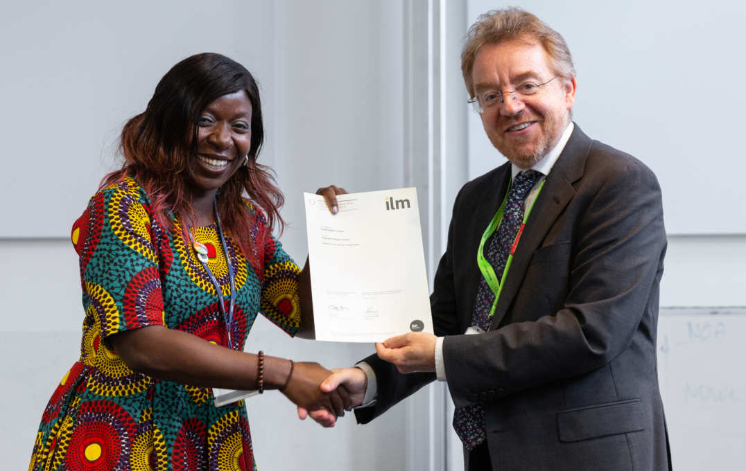 woman collects certificate and shakes man's hand