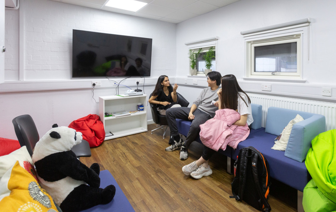 Room with students sitting on a sofa in front of a widescreen tv