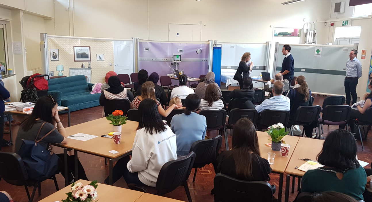 Members of the audience watch a simulation of a parent's journey through the healthcare system when their child becomes ill