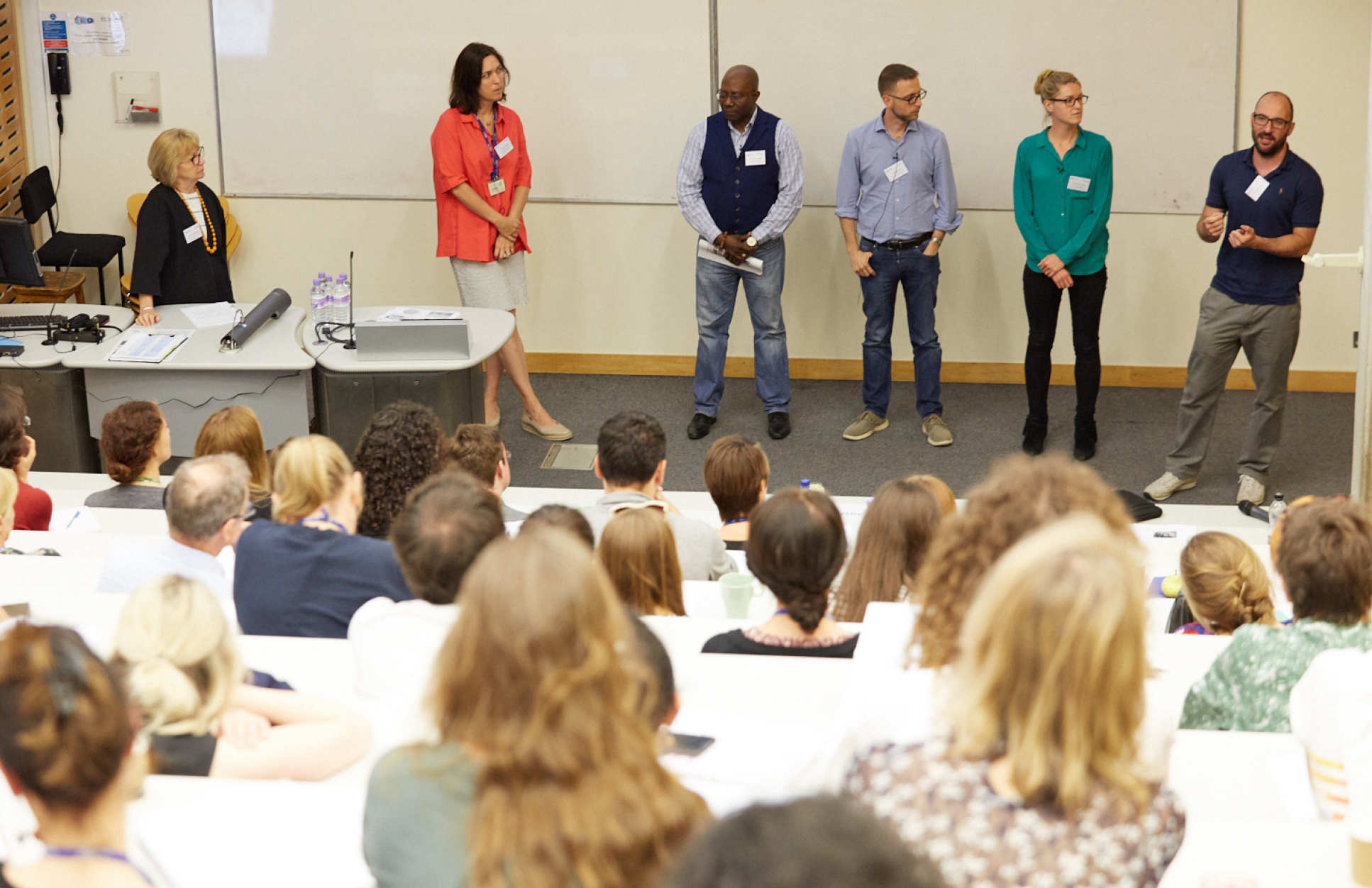 people standing in a line presenting at the front of a lecture theatre