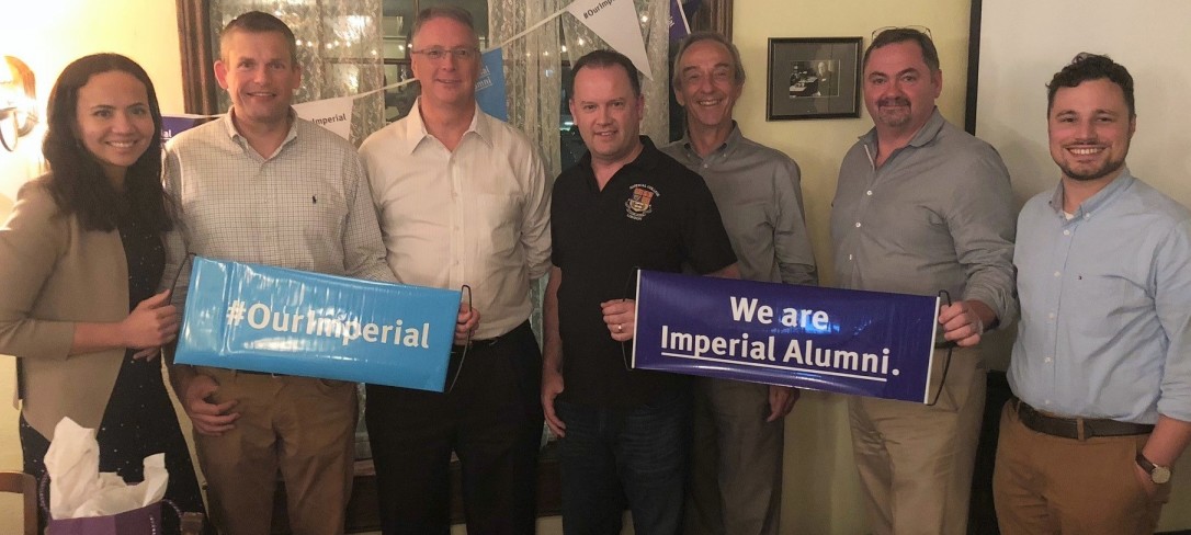 A group of Imperial alumni holding banners and smiling