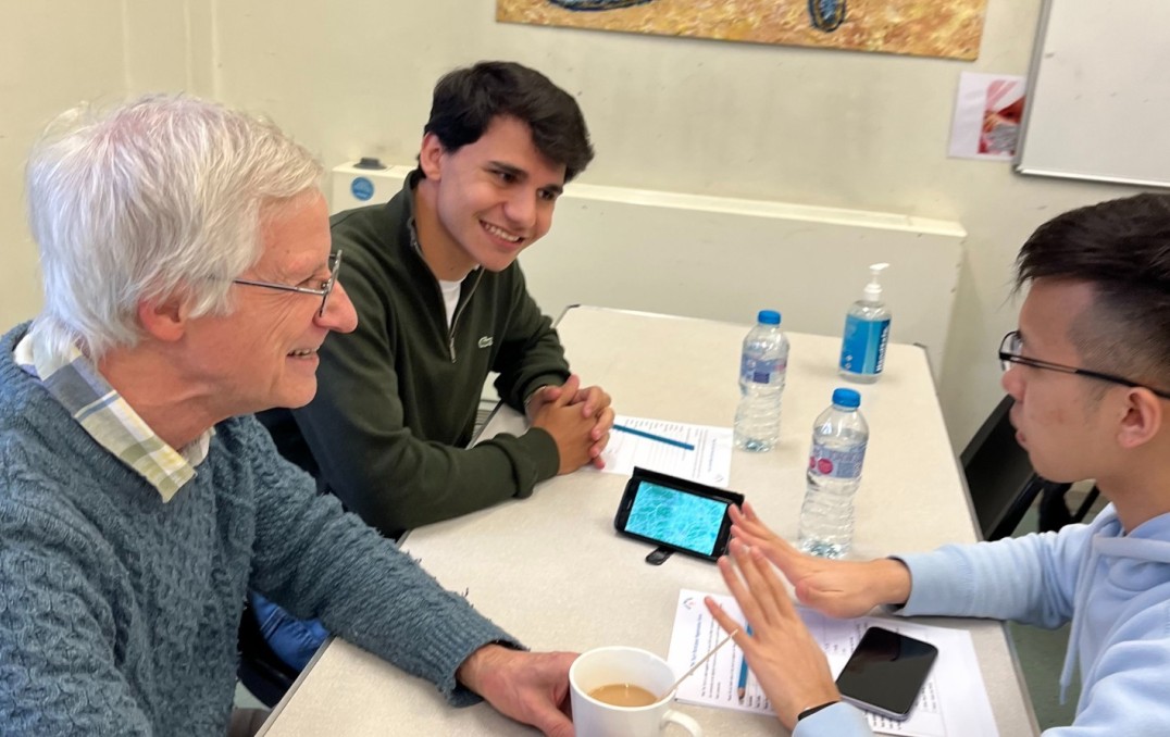 Two 'What the Tech?!' volunteers speaking to a programme participant.