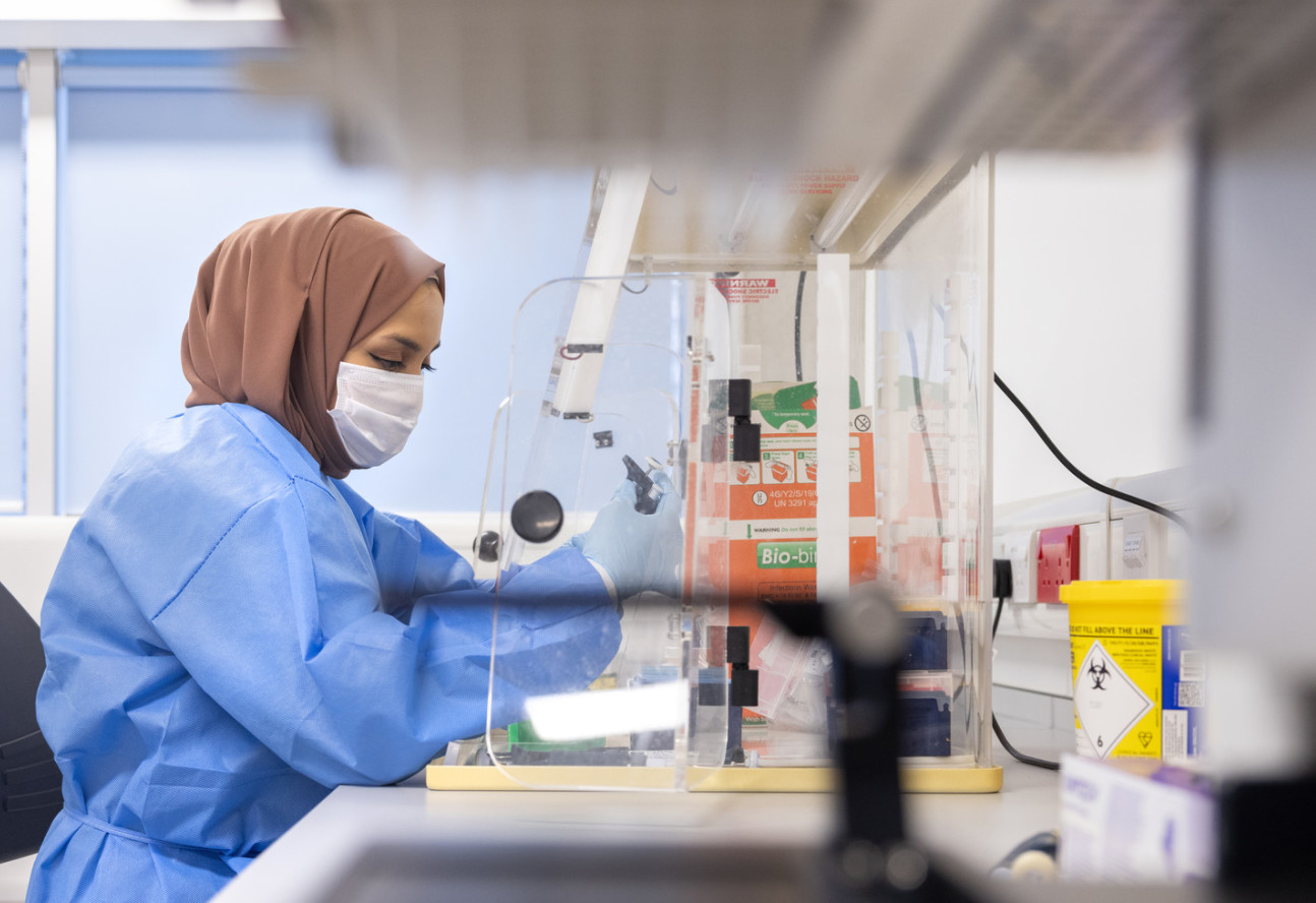 Lady in headscarf and face mask working in laboratory