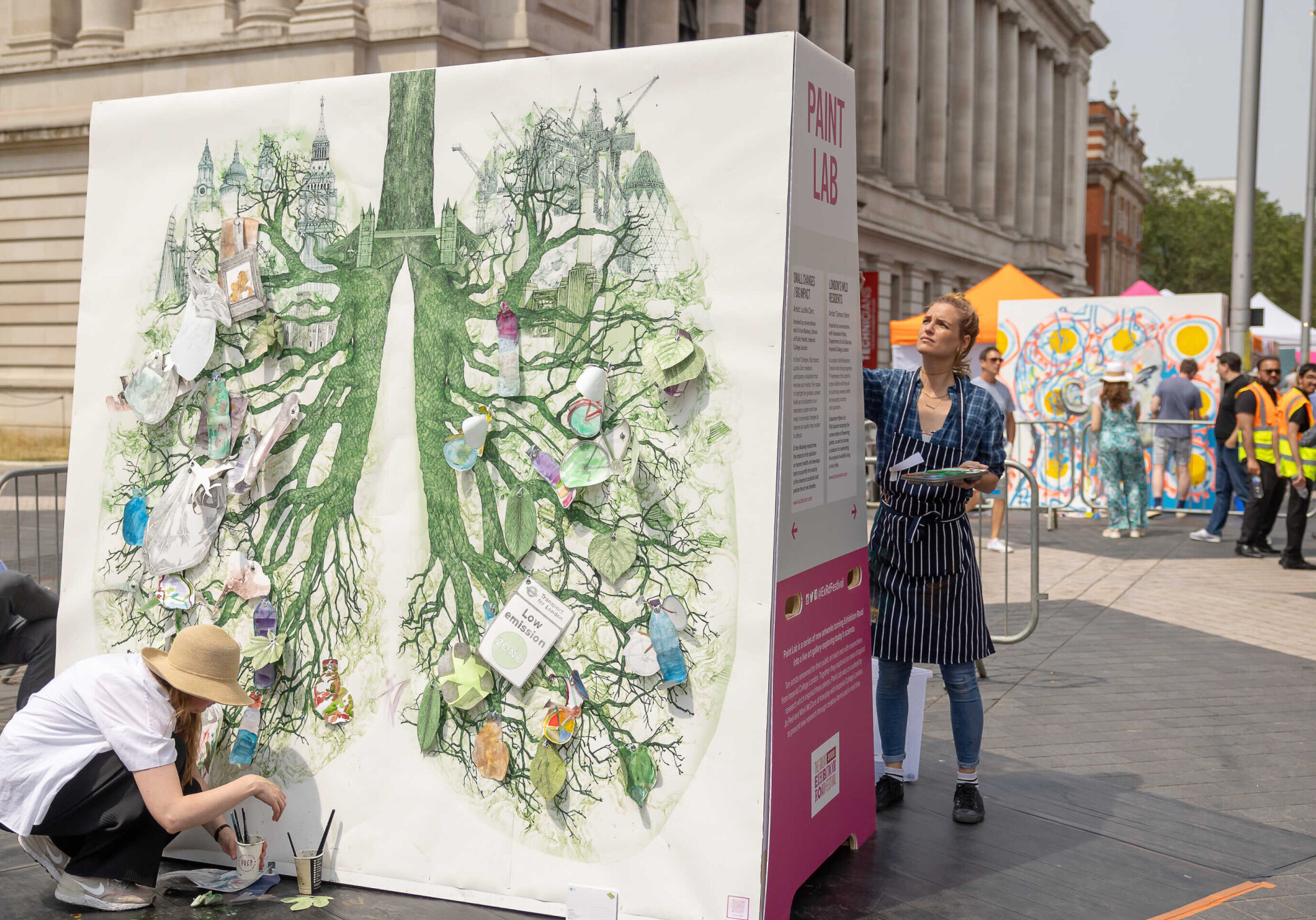 Artist painting green lungs on large canvas on Exhibition Road