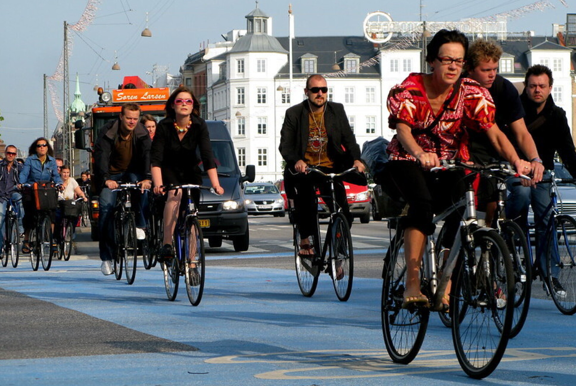 People cycling through a bike lane during rush hour.