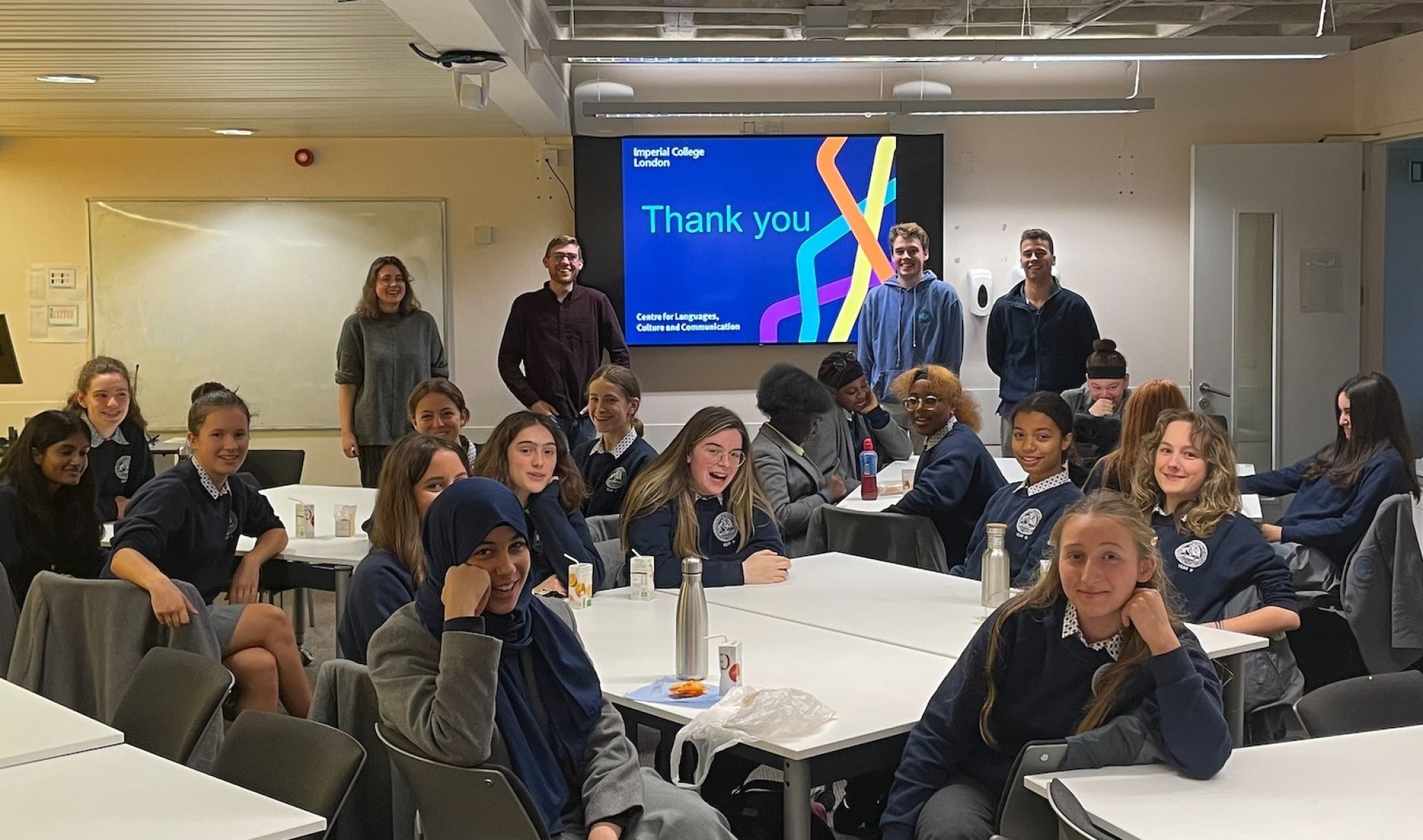 school pupils smile for photo in college classroom