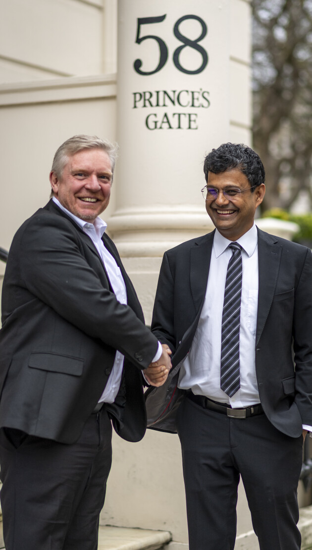 Atish Dabholkar and Mark Howells laughing and smiling whilst shaking hands outside 58 Prince's Gate in South Kensington.