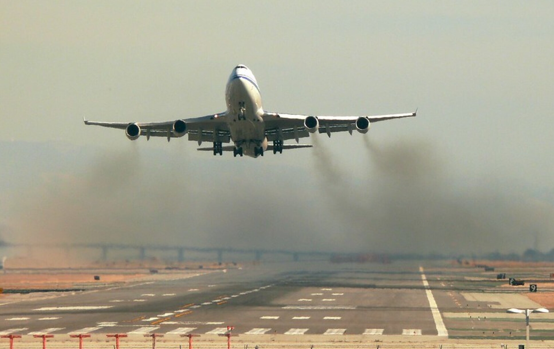 An airplane taking off while releasing carbon pollution.