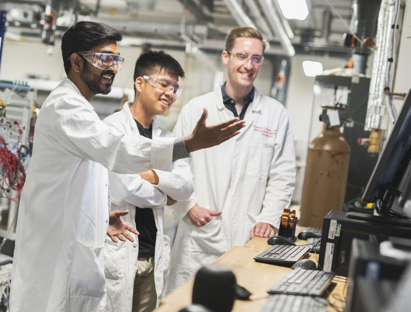 Three researchers in white coats looking at screen