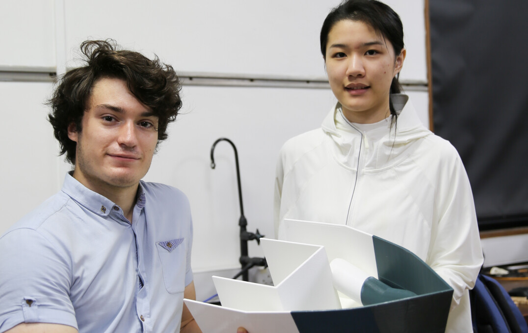 Two students hold their prototype boat