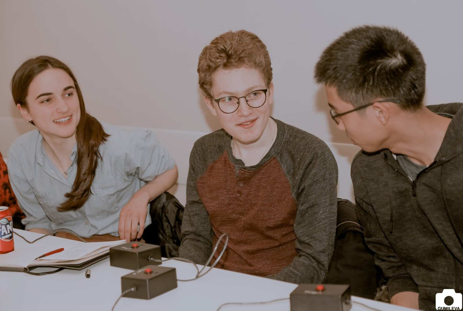 three students chat with buzers on table