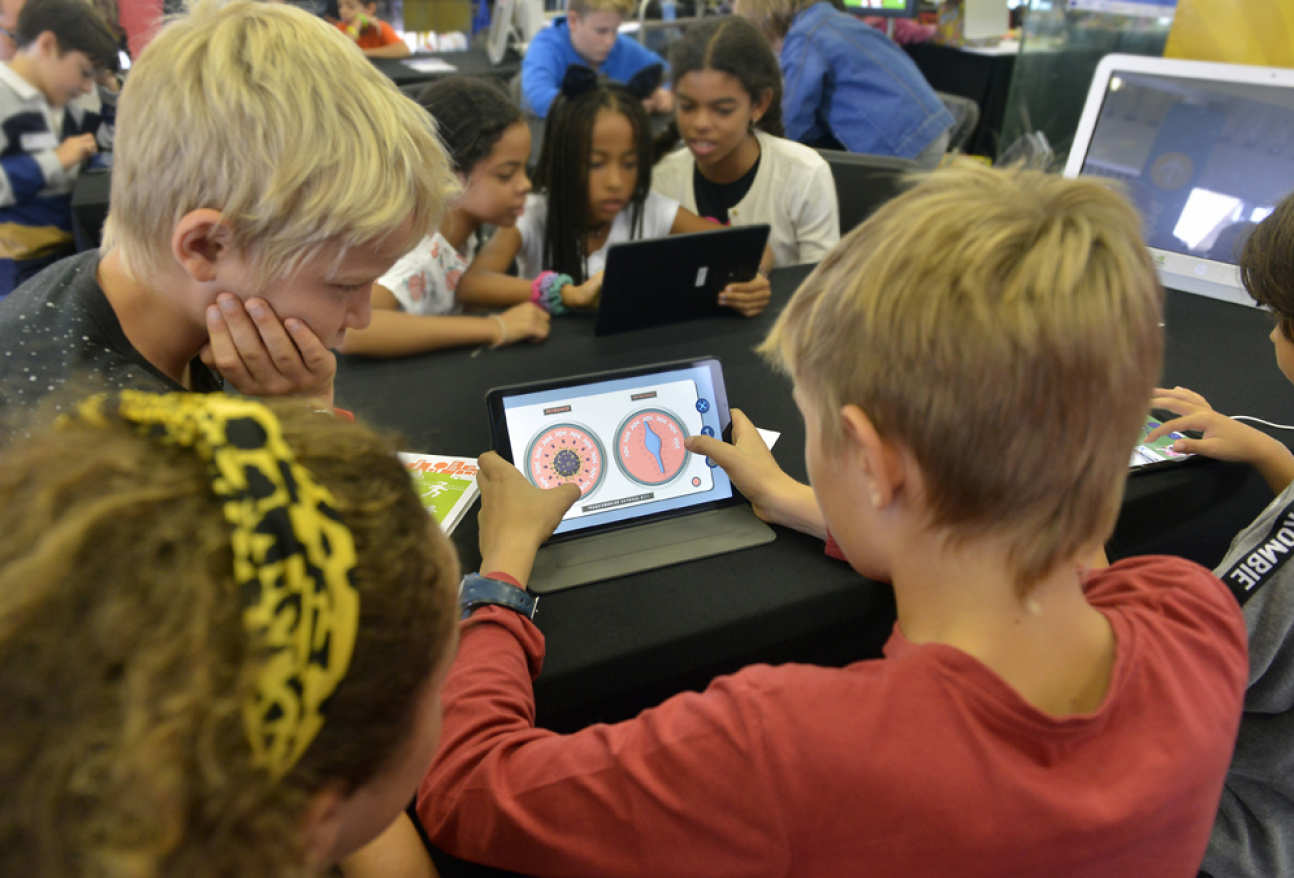 Children playing Battle for Cattle game on tablet