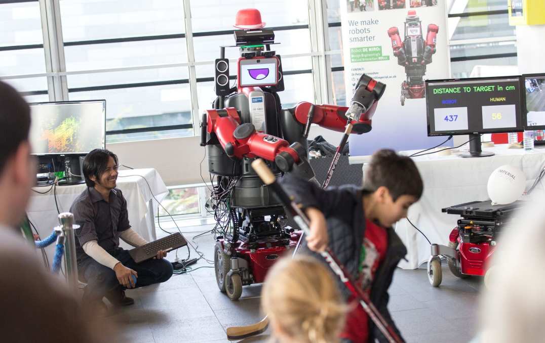 A red robot plays ice hockey with a child