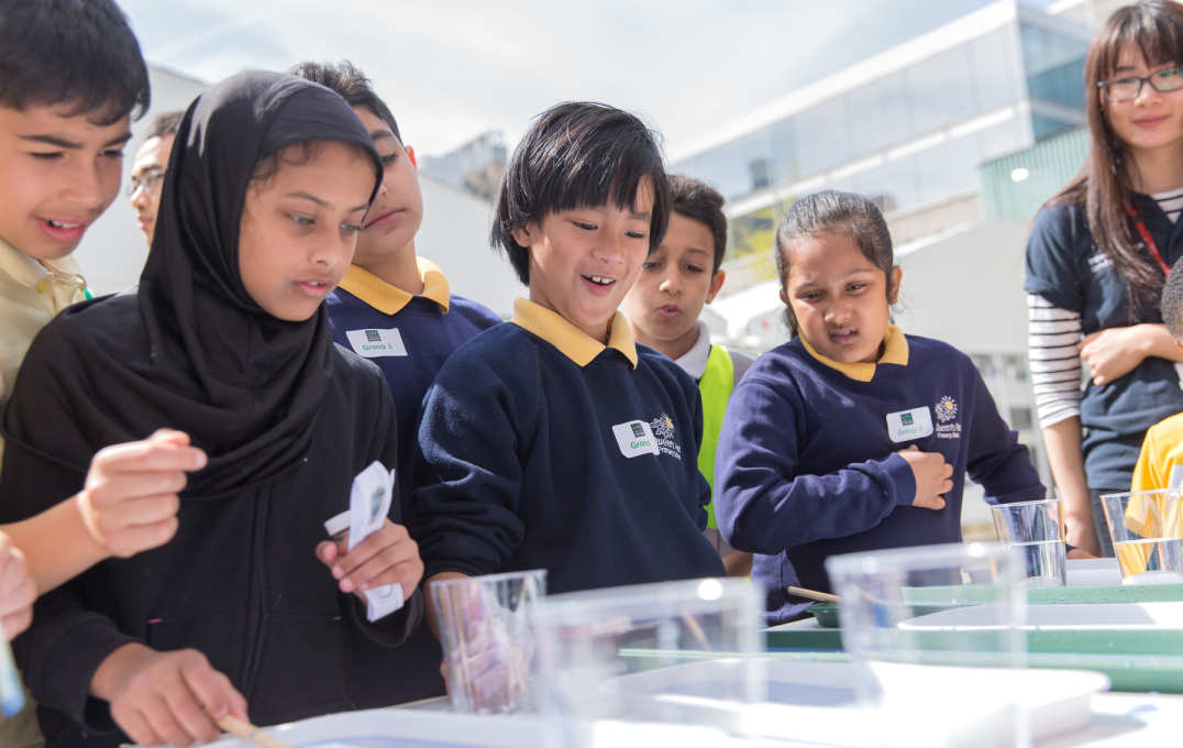 Young children look down at a science exhibit on a table