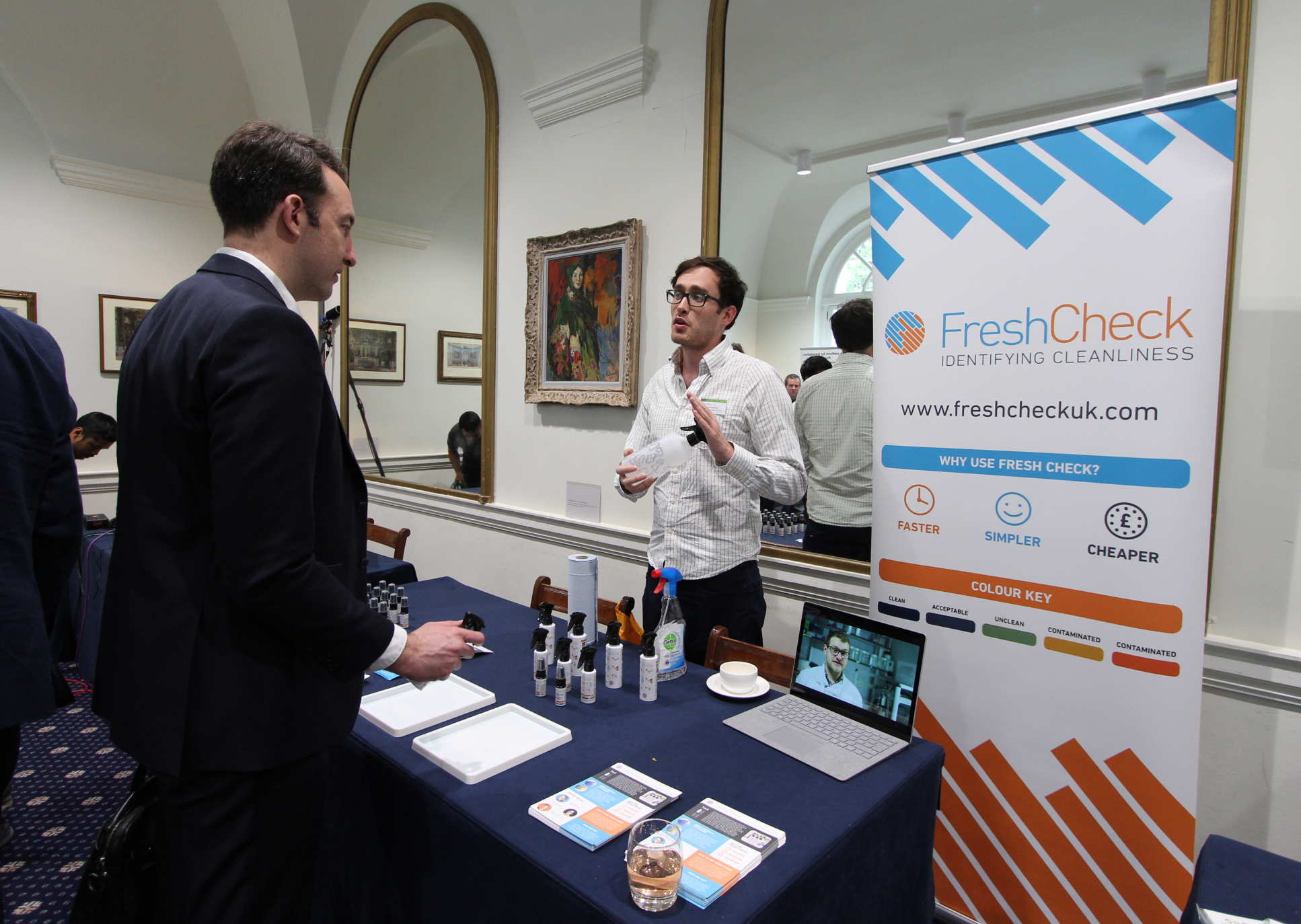 Man with small bottles of samples talking to a man over a table