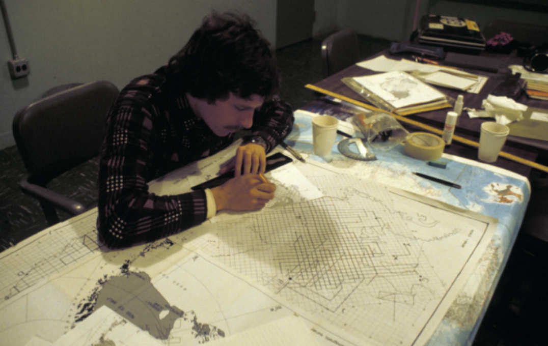 A man drawing lines on a map of Antarctica