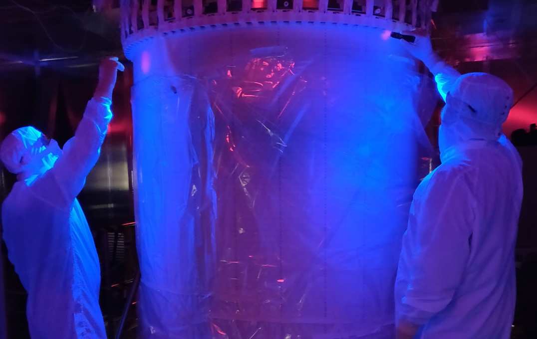 People in hazmat suits shine UV torches at the cylinder