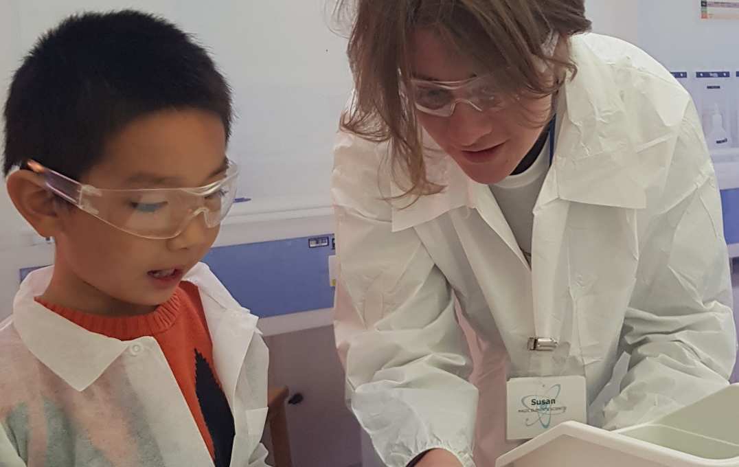 Researcher and boy lean in over an instruction sheet