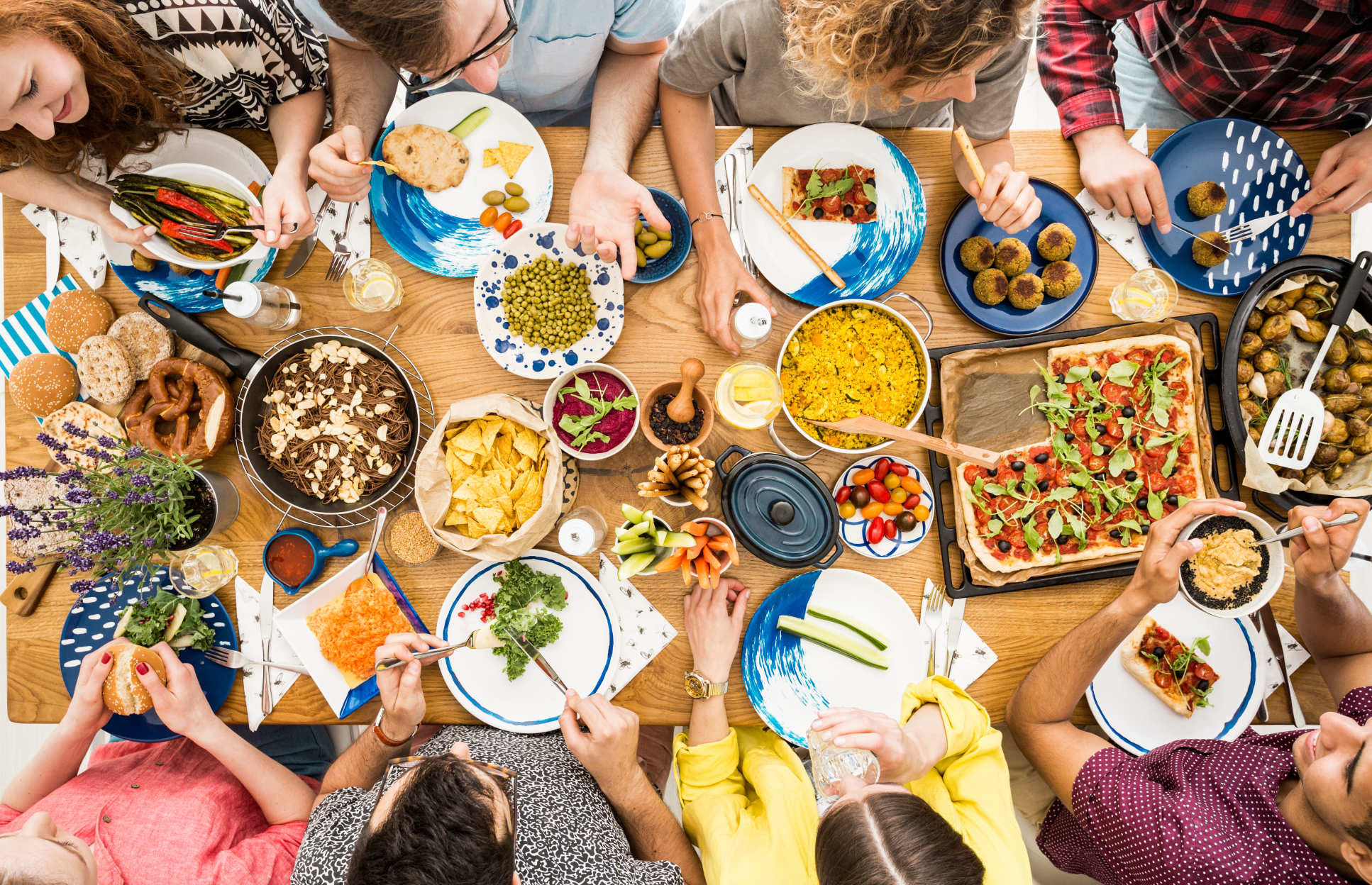 A dining table with lots of people and plates of food